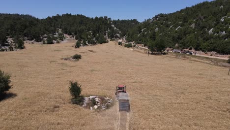 Drone-view-of-a-combine-harvester-harvesting-ripe-wheat-planted-in-agricultural-land,-convenience-in-agriculture