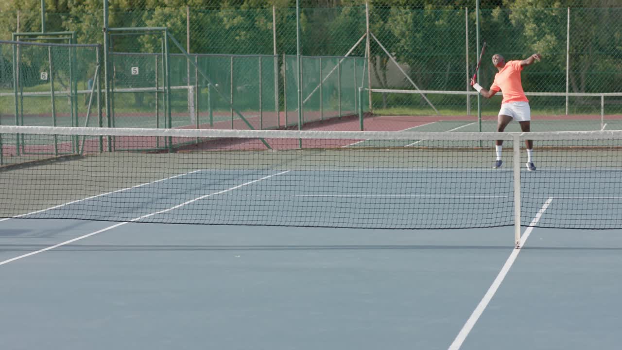 jugador de tenis afroamericano que sirve la pelota al oponente en la cancha al aire libre en cámara lenta
