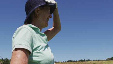 blanke senior vrouw met een golfclub op zoek naar een afstand op een golfbaan op een heldere zonnige dag