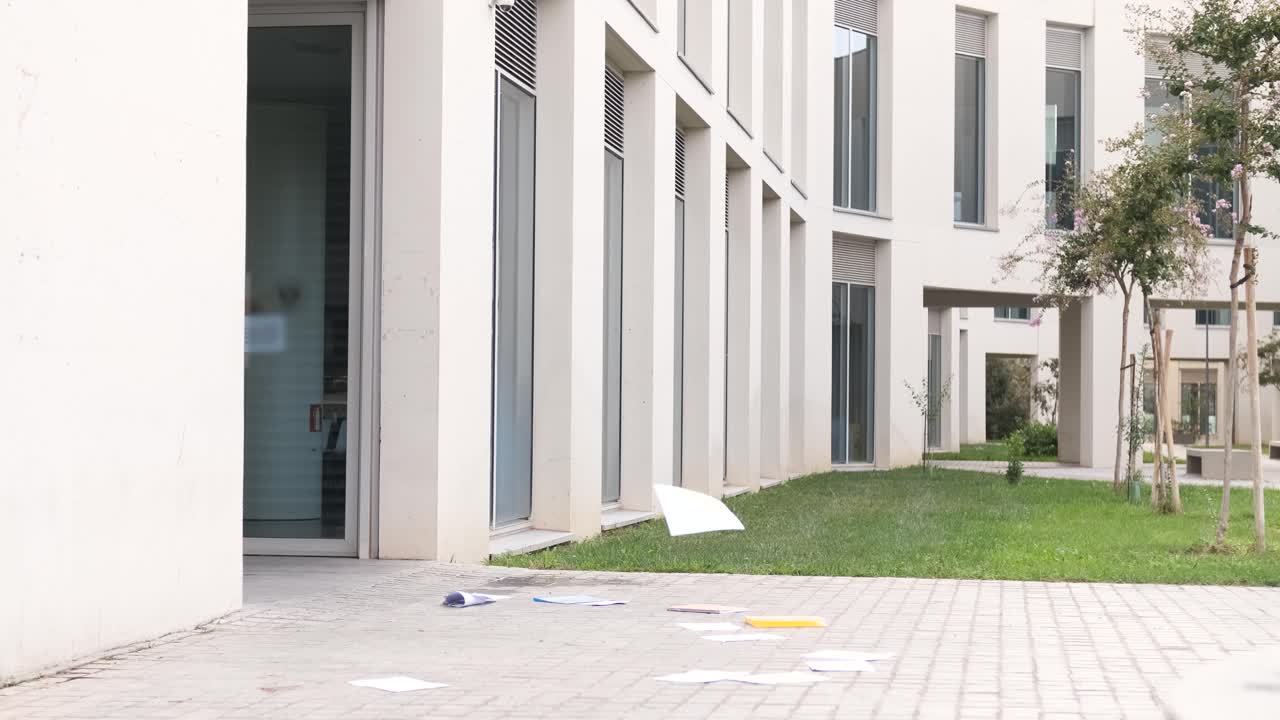 Excited students throwing papers outside university building