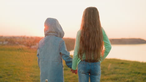 children boy and girl hold hands in rain at countryside toddler brother and preschooler sister look