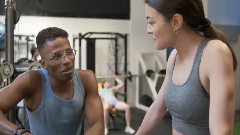 man and woman discussing exercise routine in gym