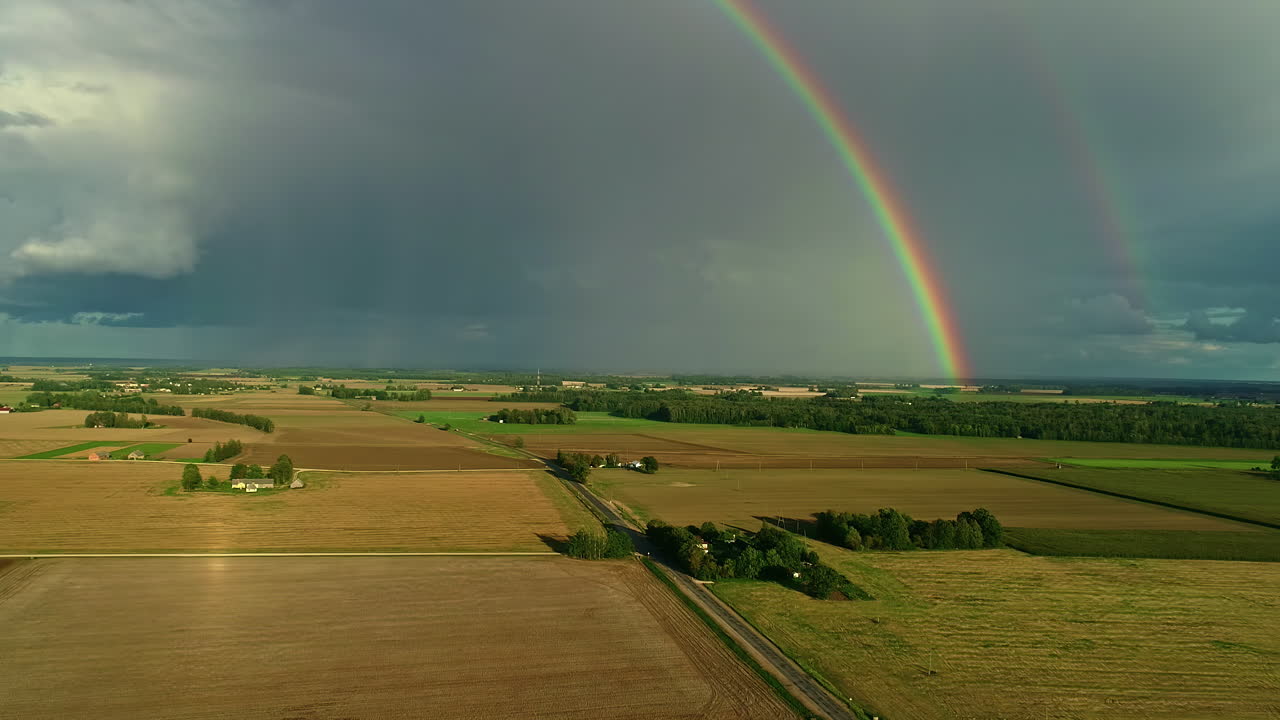 hermosa toma de dos arco iris en el horizonte, rodeado de un campo, un camino y la naturaleza
