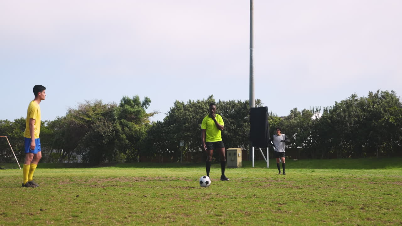 Playing soccer on field, athlete in green jersey kicking ball while teammates watch