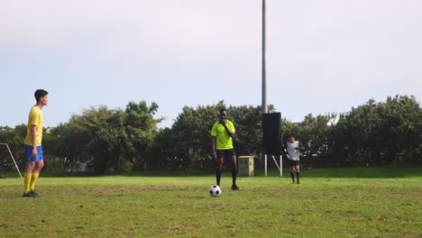 playing soccer on field, athlete in green jersey kicking ball while teammates watch