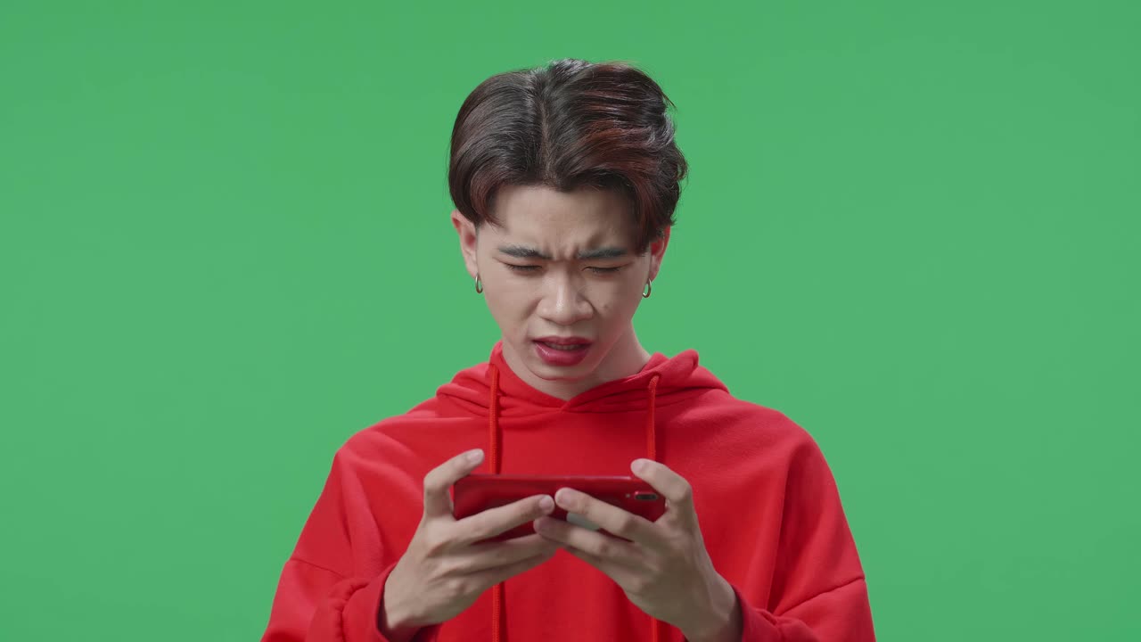 Upset Asian Transgender Male Losing Mobile Phone Game On The Green Screen Background