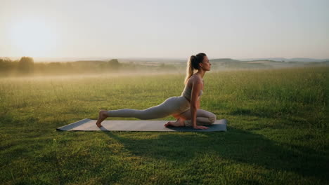 woman practicing yoga outdoors in a misty field at sunrise