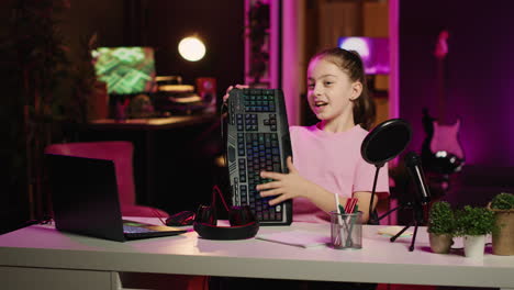 Kid-influencer-in-studio-using-camera-to-review-gaming-keyboard,-mouse-and-headphones