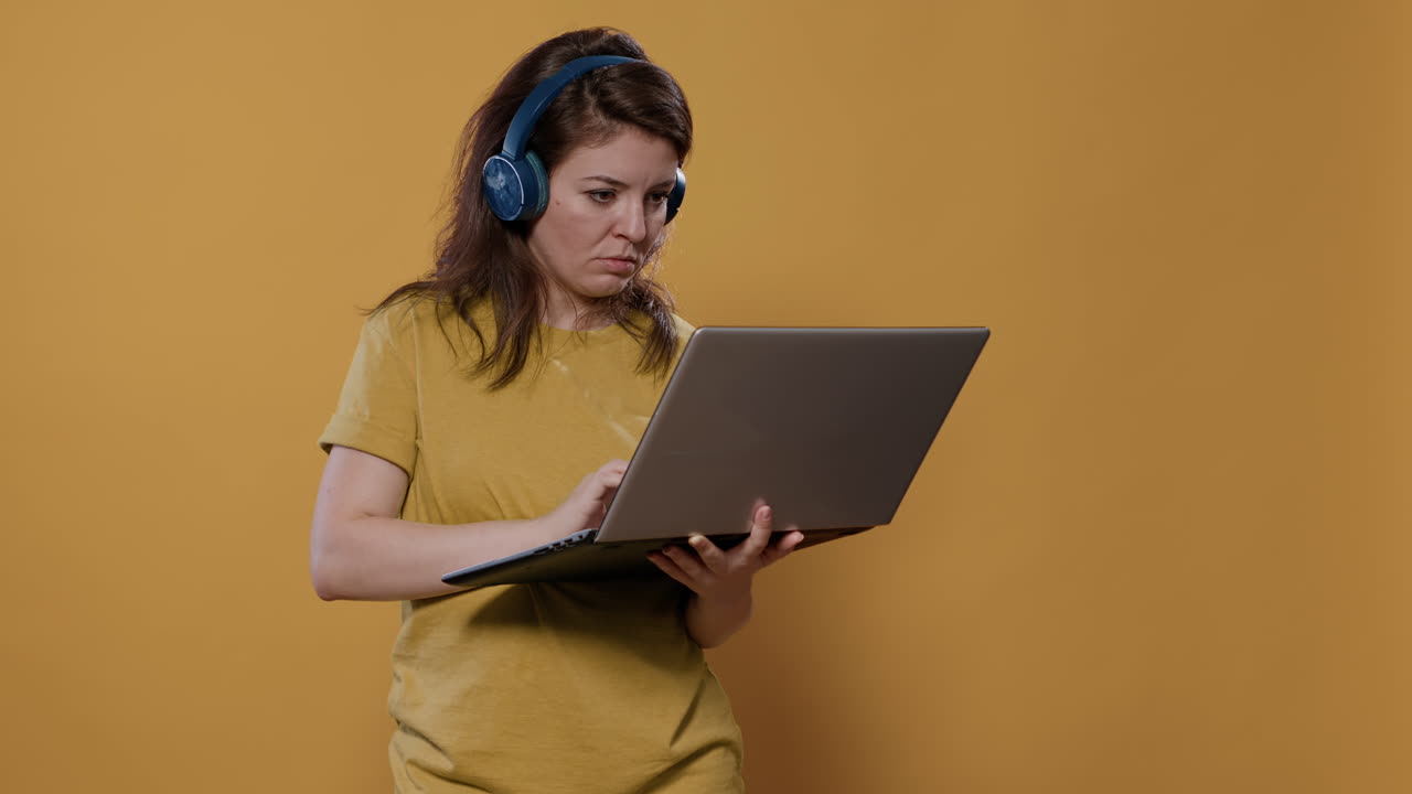 Woman working on a laptop wearing headphones