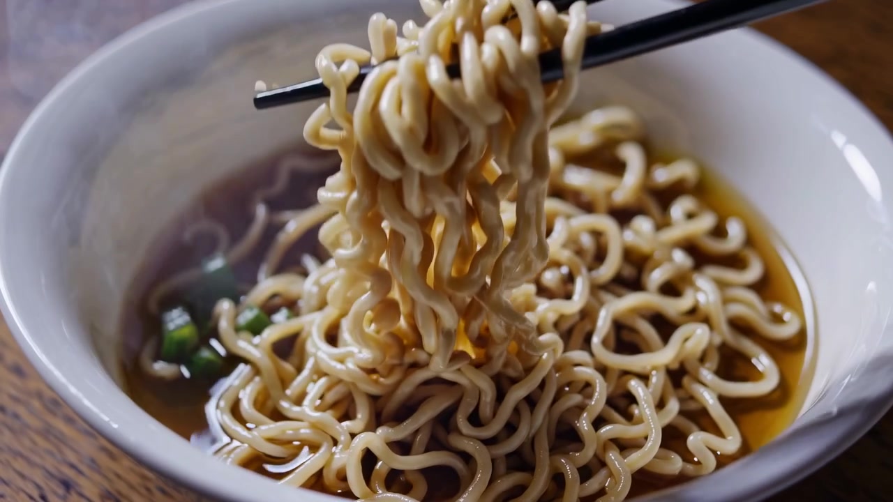 丼から箸で熱いラーメンを持ち上げる人
