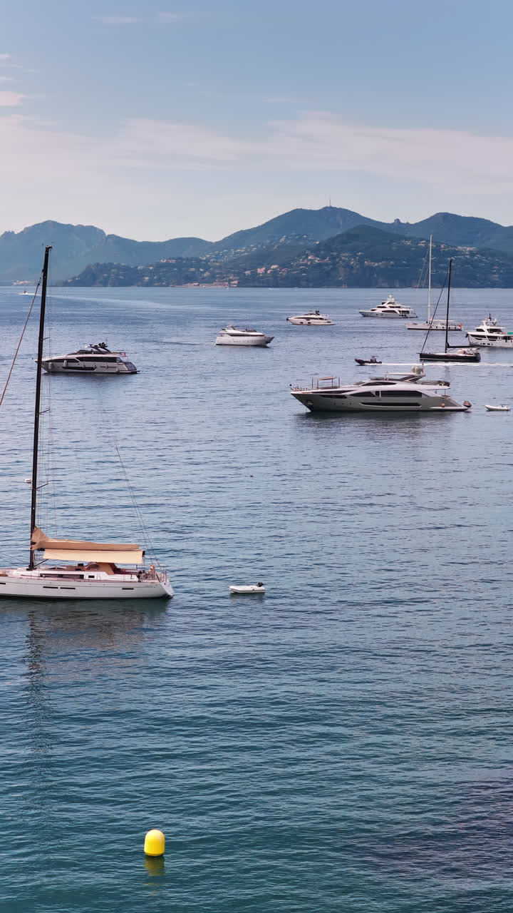 Vista aerea con drone di decine di yacht e barche a vela ancorate nelle calme acque turchesi al largo di Cannes. Verticale