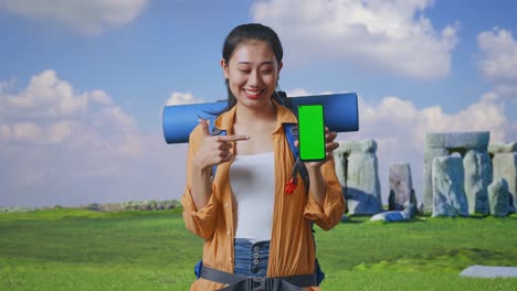 woman traveler showing green screen phone at stonehenge