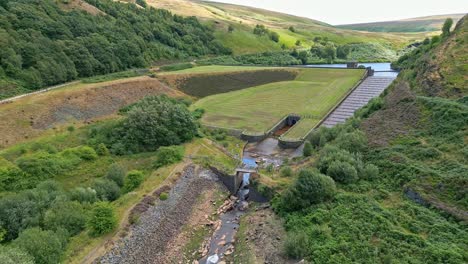 aerial drone video footage of a reservoir dam wall showing overflow structures
