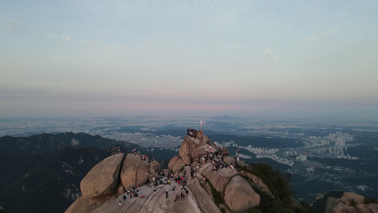 관광객들은 서울의 아름다운 일몰을 바라보며 북한산을 오른다