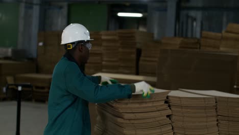 worker handling cardboard sheets in a warehouse