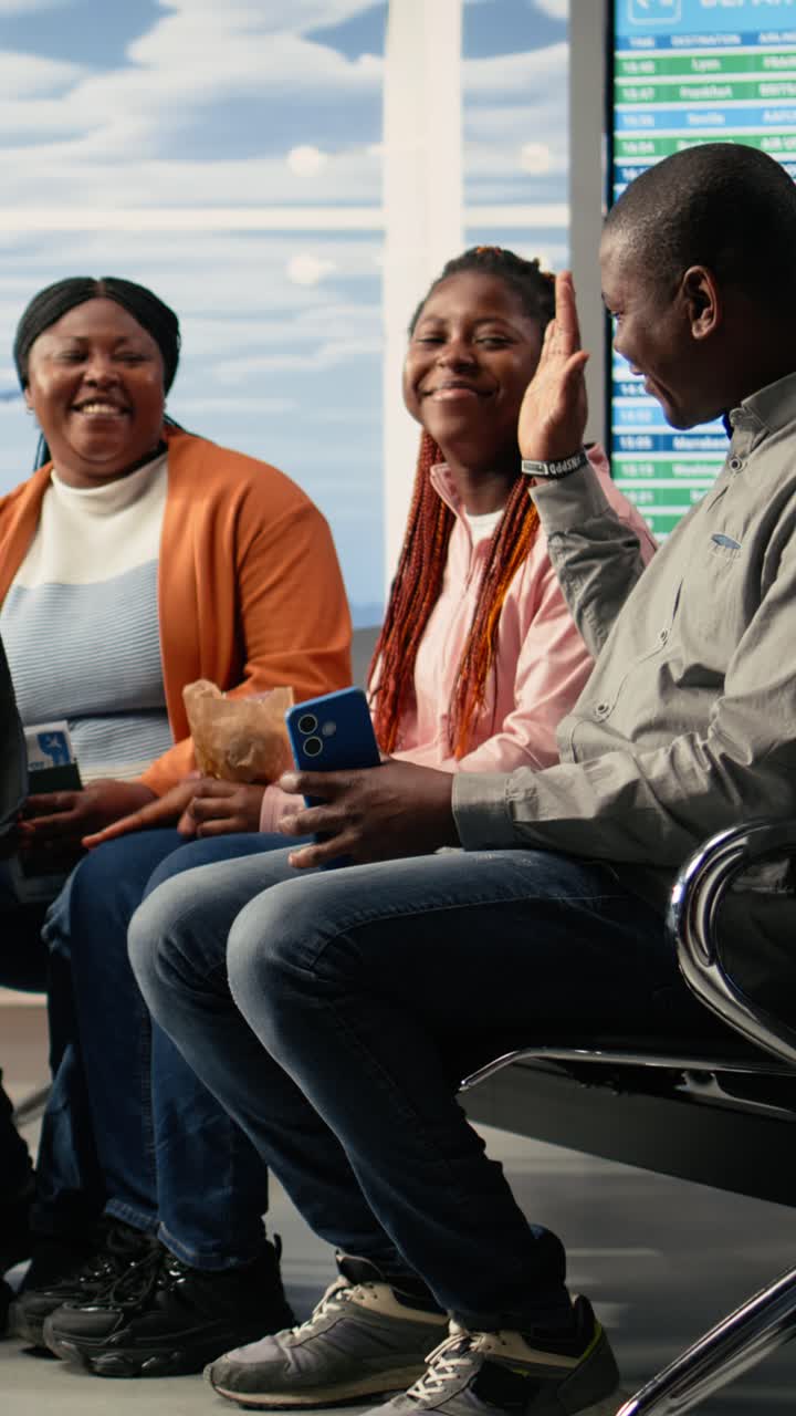 Vertical Video Black Parents And Teenager Seated On Bench In Bright Airport Lounge Area