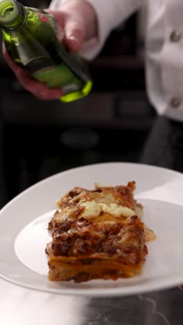 chef pouring olive oil over a plate of lasagna