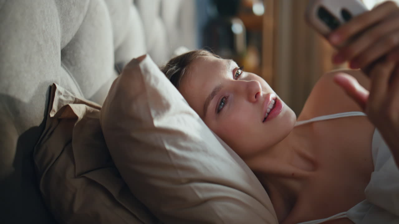 Young woman using her phone in bed in the morning