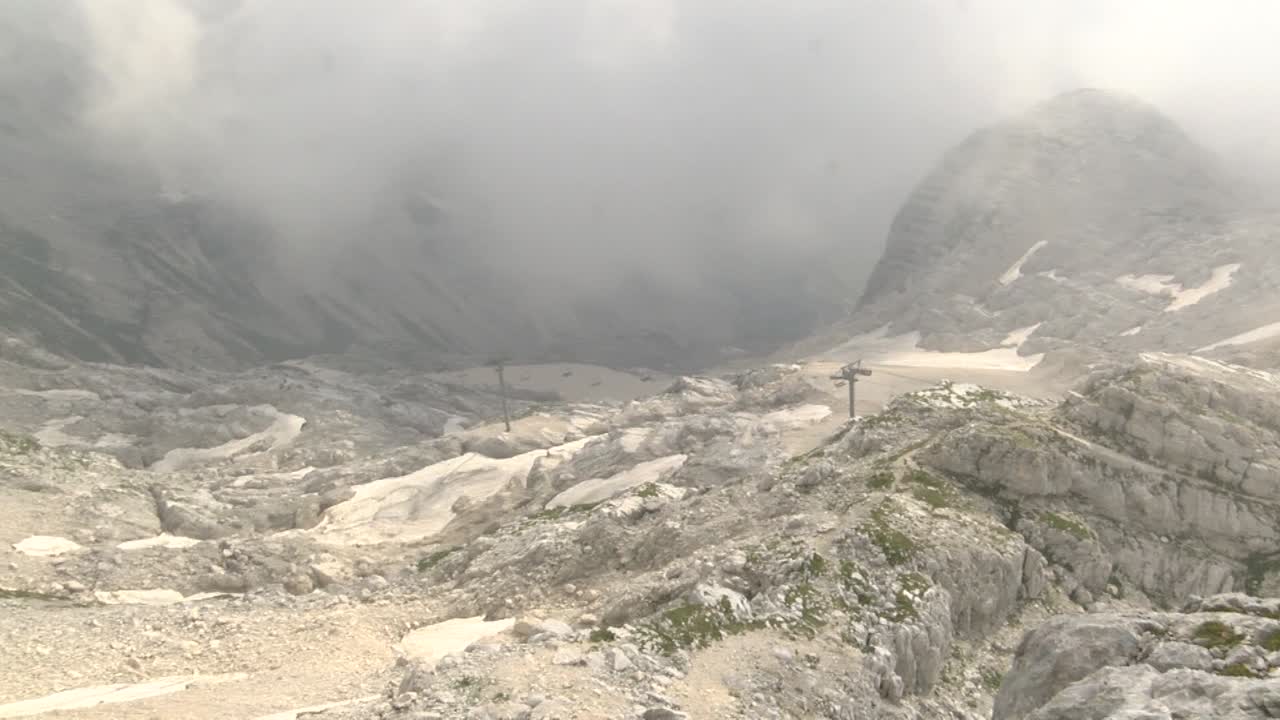 霧の春の日の石灰岩の山々の左パン。遠方には稼働中のチェアリフトが見え、壮大な景色。