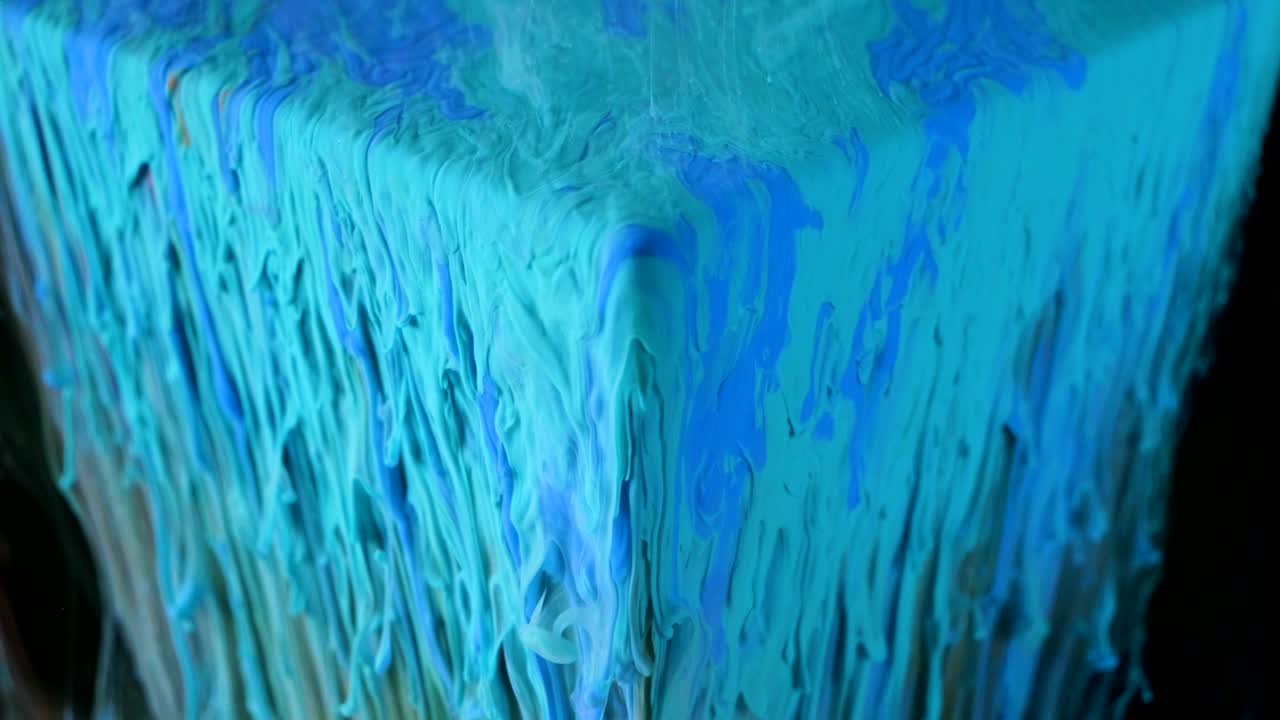 pintura de tinta multicolor fluye lentamente desde el cubo bajo el agua