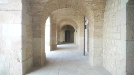 Montjuic-Castle-in-Barcelona,-forward-video-through-stone-hallway-at-inner-courtyard-of-old-medieval-castle-fortress