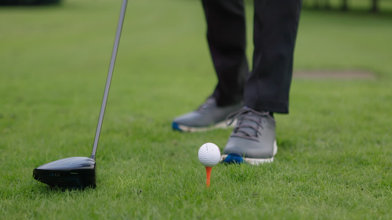 A golfer placing a golf ball on a tee