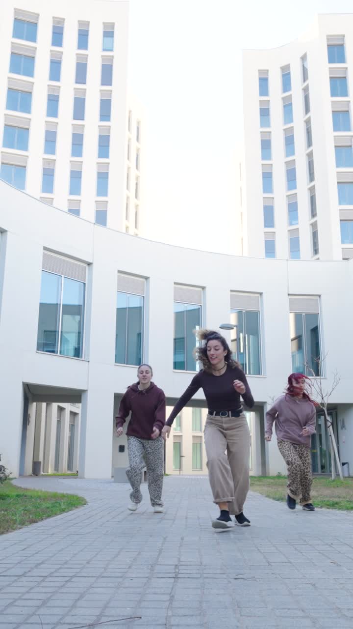 Young women dancing outside modern building
