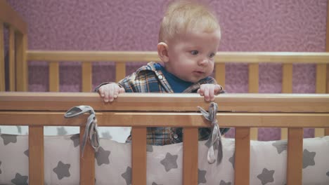 little boy leans on cot with star patterned linen at wall