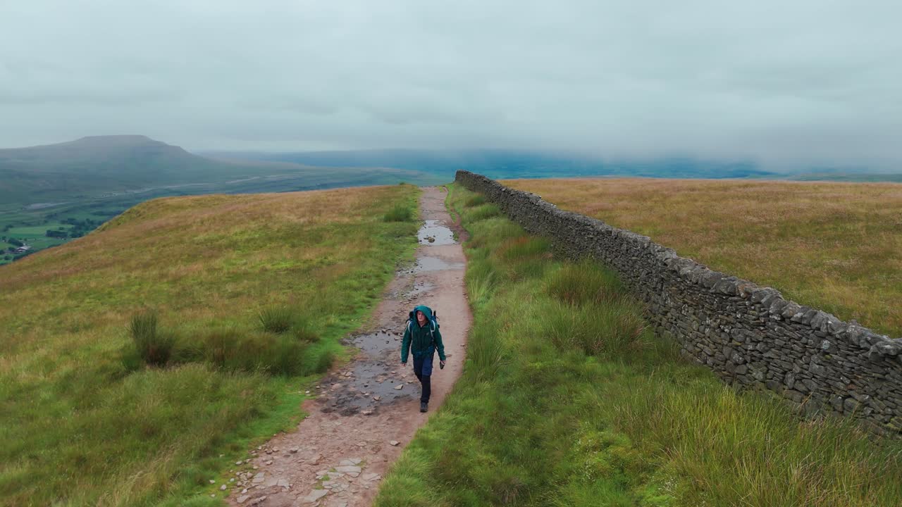 Hiker on a path with a stone wall
