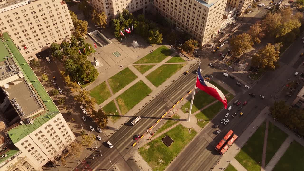 Plaza de La Ciudadania, Citizenry Square, La Moneda Palace, giant Chilean flag waves, bicentenary, Chile. Aerial tilt-down orbiting