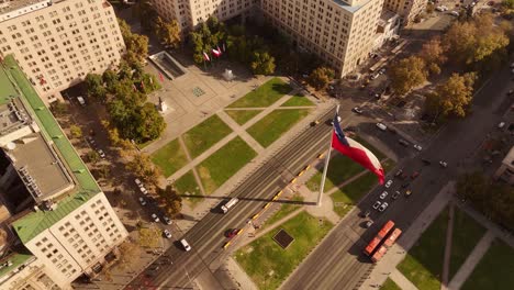 plaza de la ciudadania, citizenry square, la moneda palace, giant chilean flag waves, bicentenary, chile. aerial tilt-down orbiting