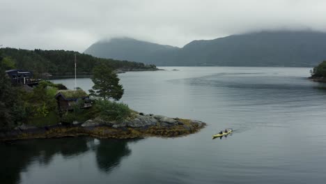 Toma-Aérea-De-Drones-De-Kayakistas-En-Un-Enorme-Lago-Con-Montañas-Al-Fondo