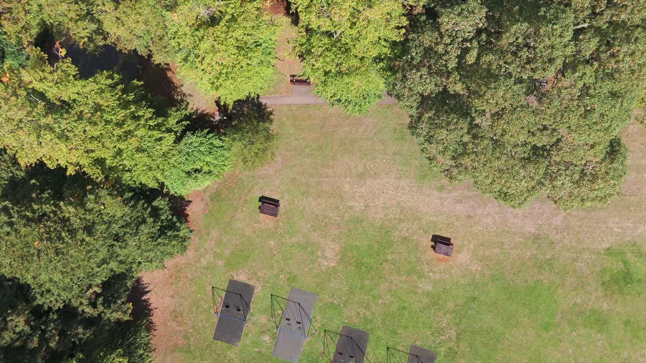 The grassy, lawn area features outdoor, open-air fitness, exercise equipment mats and two small benches