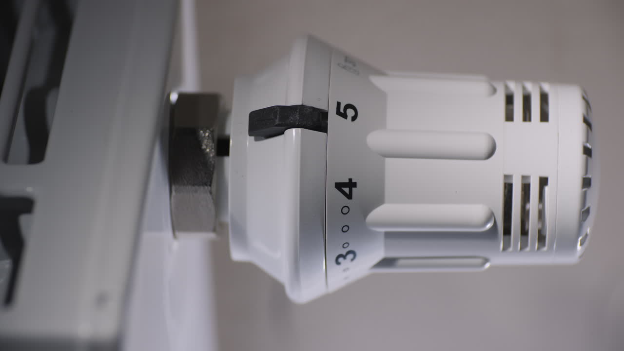 la mano masculina ajusta el nivel de temperatura en el termostato del radiador de calefacción