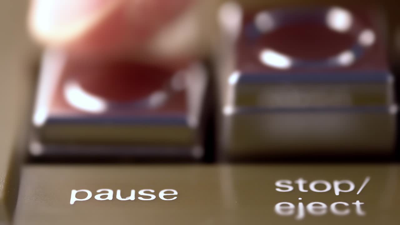 botón de pausa de un grabador de cinta de época presionado por un macro de dedo