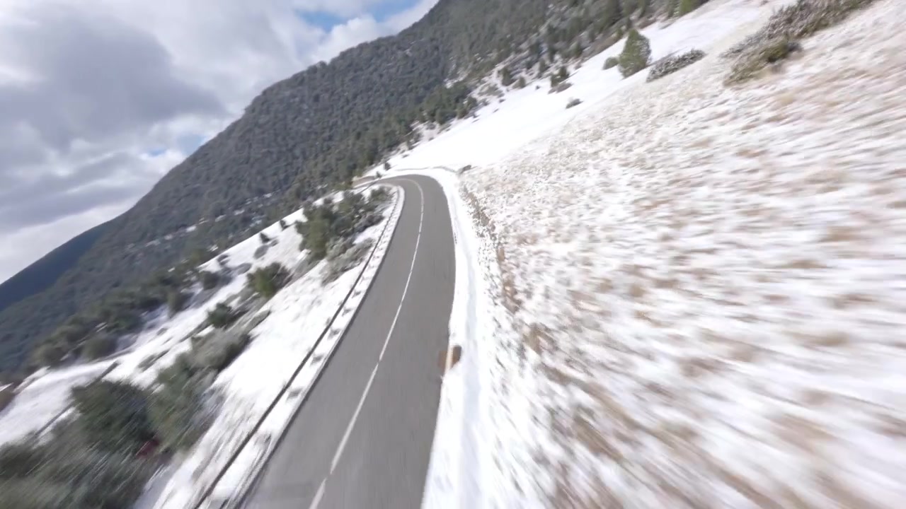 High precision fast FPV drone flying down alpine forest mountain, snow-covered