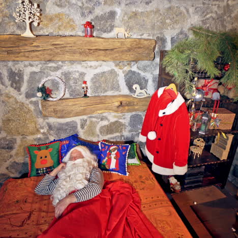 santa claus is sleeping in specially decorated room in his bed. he is holding his hand under his cheek. christmas spirit concept close up video. christmas eve. new year is coming. video from above.