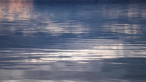 The-setting-sun-and-white-clouds-are-reflected-on-the-rippled-water-surface