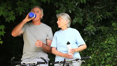 elderly couple with bikes taking a break to drink