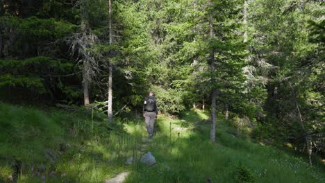 Slow-motion-of-man-walking-on-a-rocky-path-inside-mountain-forest