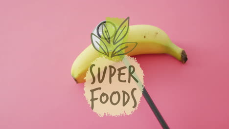 super foods text animation over banana on pink background