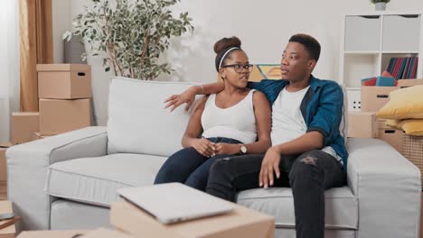 a married couple sits on the couch after moving, embrace each other, relax, plan the renovation of the apartment they bought, spin visions, discuss