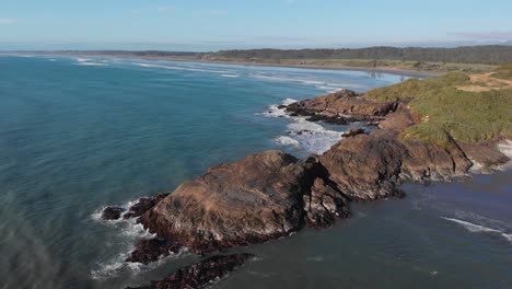 vista aérea de la costa rocosa de nueva zelanda durante la puesta de sol en 4k sobre el océano volando hacia la playa en la distancia