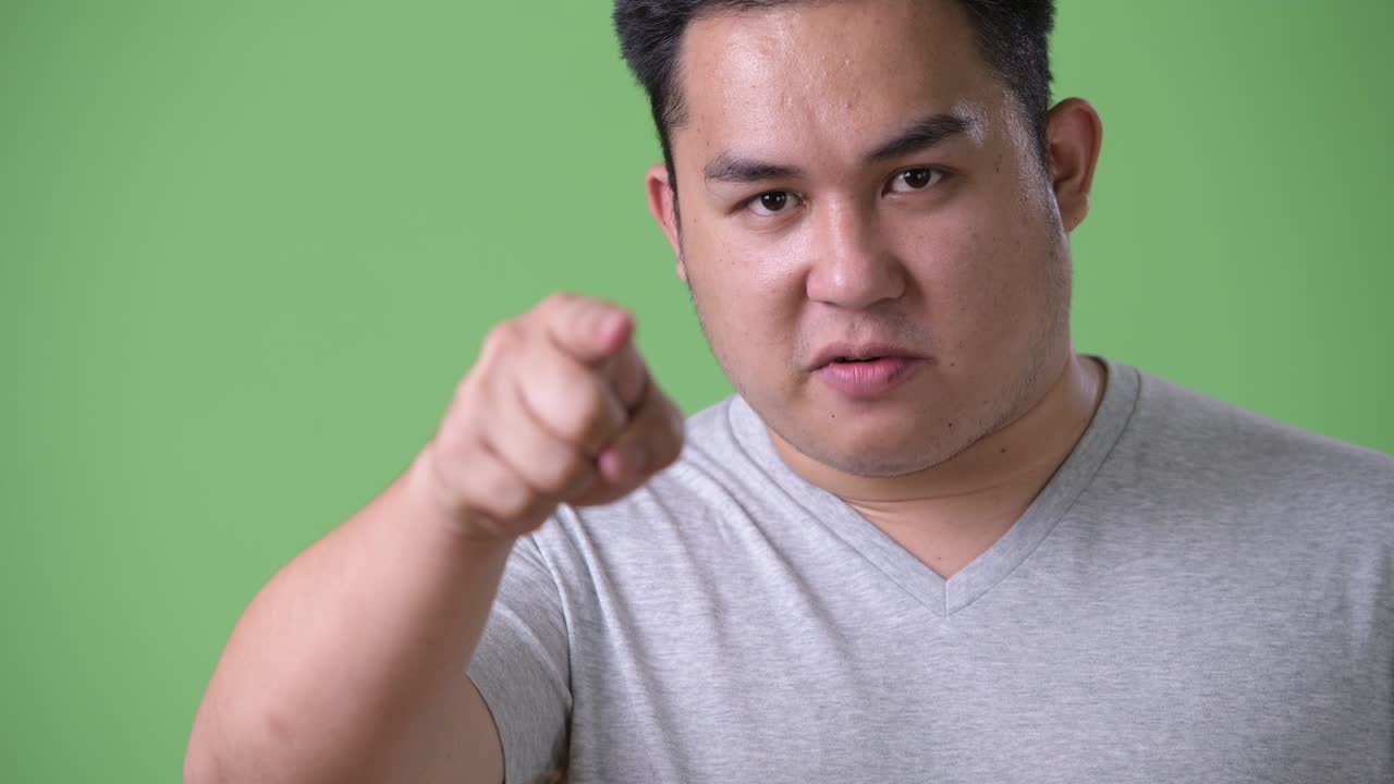 초록색 배경에 젊은 잘생긴 과체중 아시아인