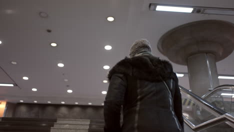 person in a jacket and hat walking on stairs and escalator