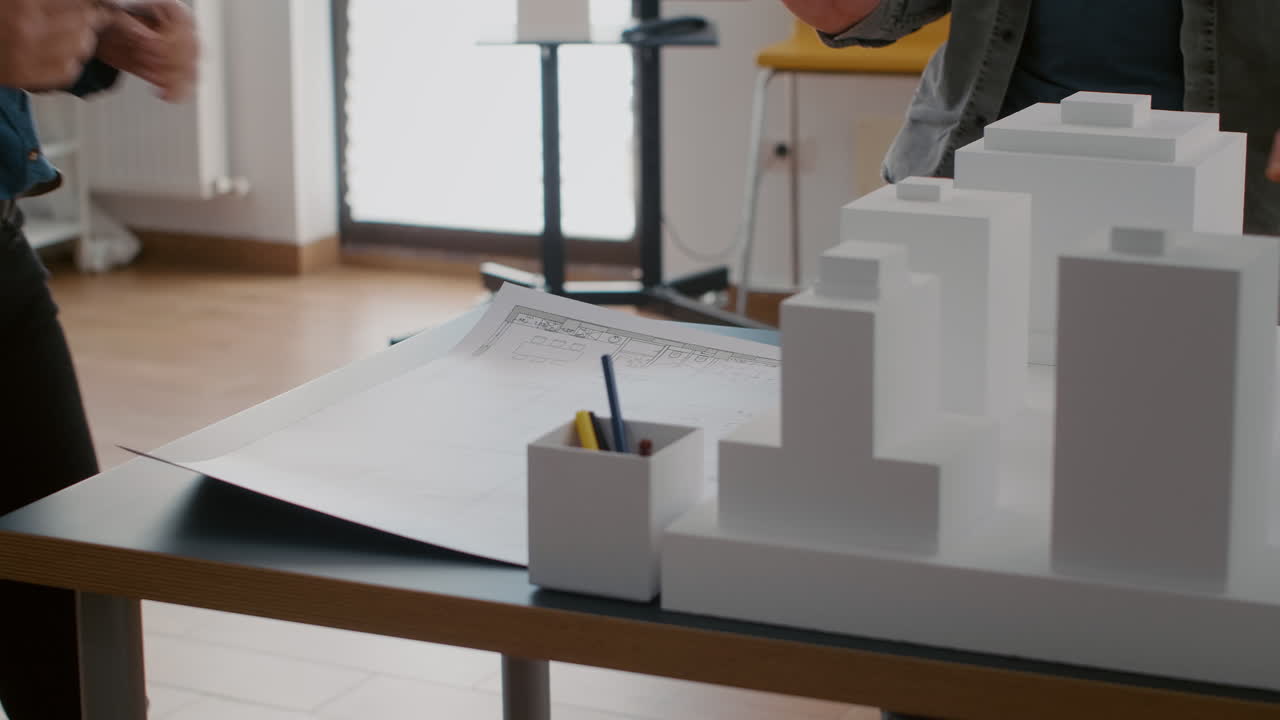 Architects collaborating on a building design with blueprint and model