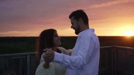 romantic couple dancing on top of a nature tower while the sun is setting.