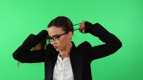 mujer de negocios sexy con gafas y traje de negocios arregla su cabello con cola de caballo y se prepara para el día de trabajo en la oficina usando guantes de boxeo