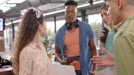 felices colegas de negocios casuales diversos con tableta y papeleo hablando en la oficina, cámara lenta