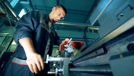 functioning metal lathe is getting regulated by a male worker with prosthetic hands